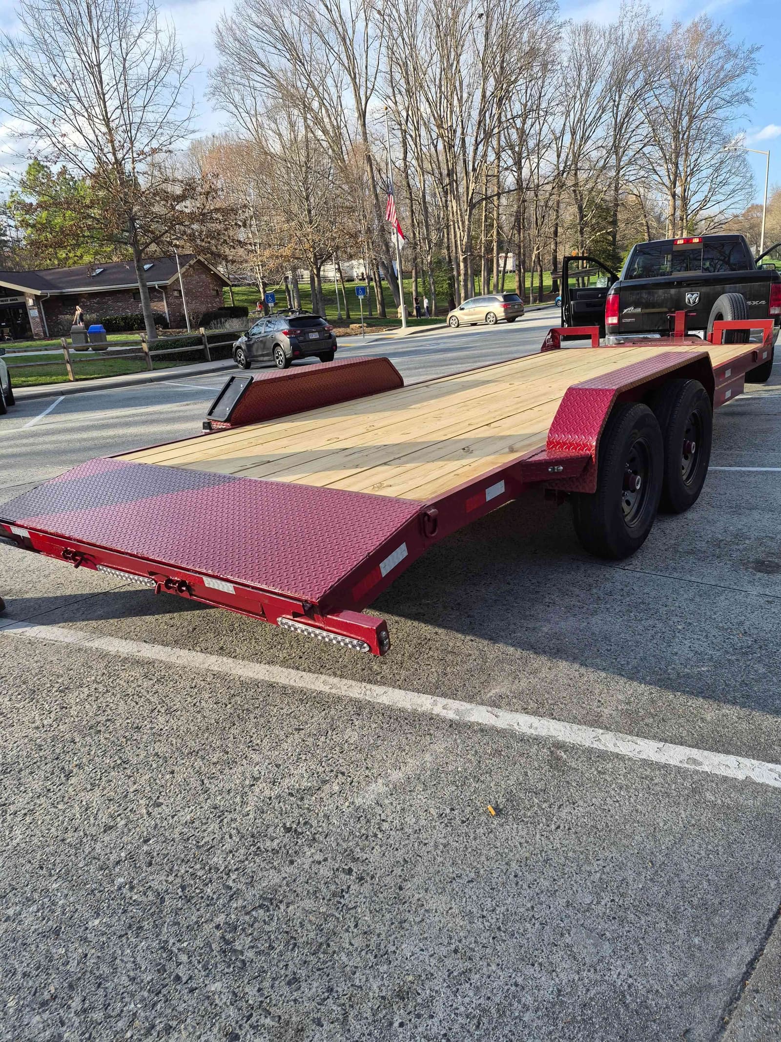 J&T Trailer Rentals red car hauler trailer with wood deck parked on a residential street in Bedford, VA
